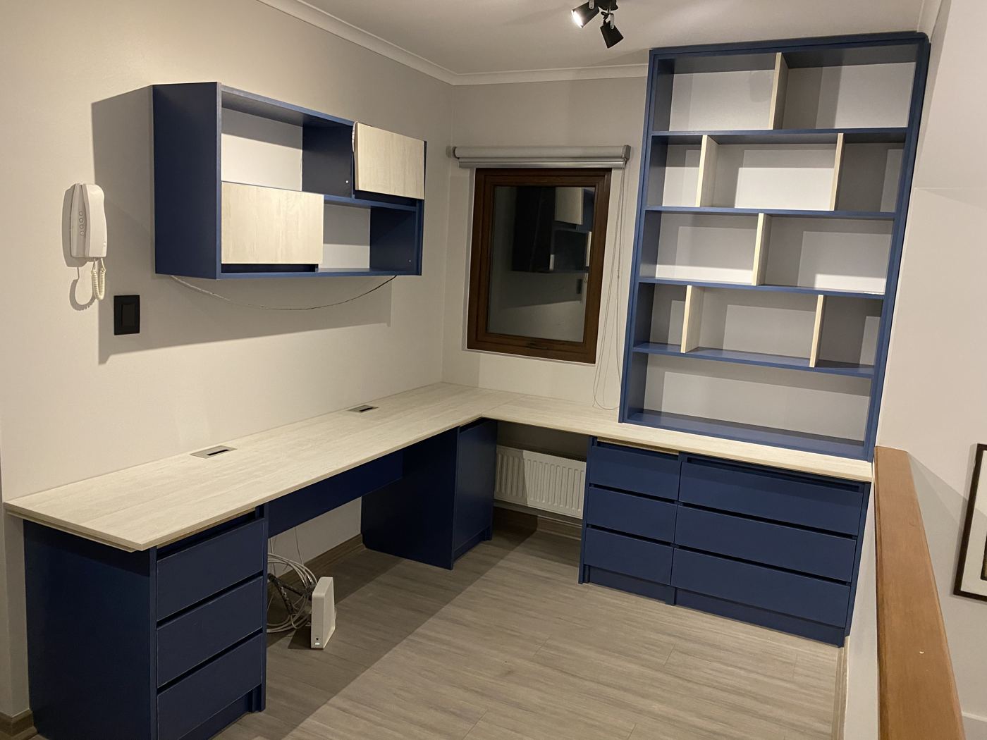 Home office en azul y blanco con escritorio en L y biblioteca